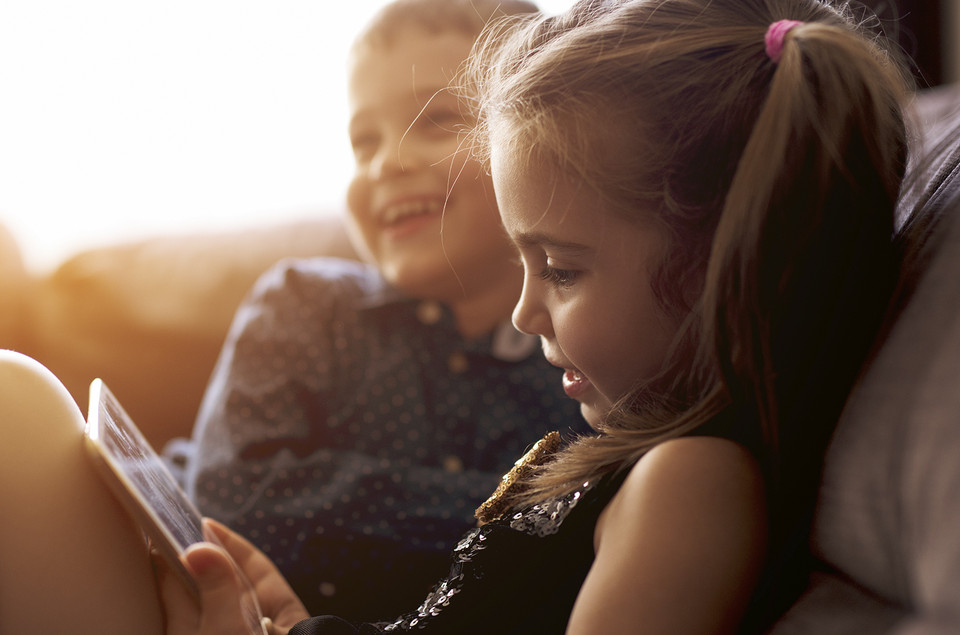 Kinderleichter Rechner, kleines Mädchen sitzt vor einem Tablet, im Hintergrund ein Junge